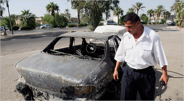 An Iraqi police officer inspecting a car destroyed in the Nisour Square shooting